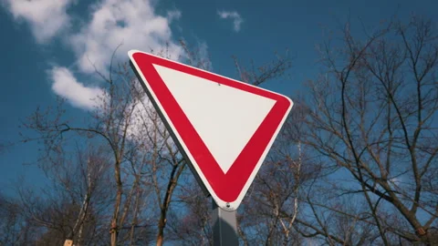 Blank Red Triangle Yield Traffic Sign Against Blue Sky And Bare Winter Trees 스톡 동영상 331861246