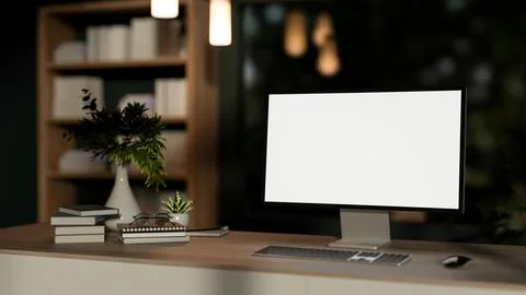 Blank screen computer with book and flower vase on wooden table in a living.. 스톡 일러스트