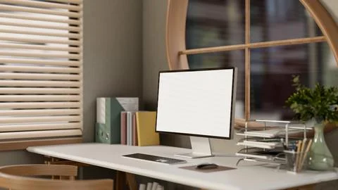 Blank screen computer with books and folders on wooden table under window i.. Stock Illustration