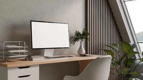Blank screen computer on wooden table with book and vase aside loft wall in.. 스톡 일러스트