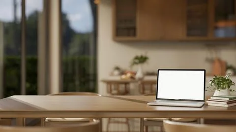 Blank screen laptop with book and potted plant on wooden table across kitch.. Stock Illustration