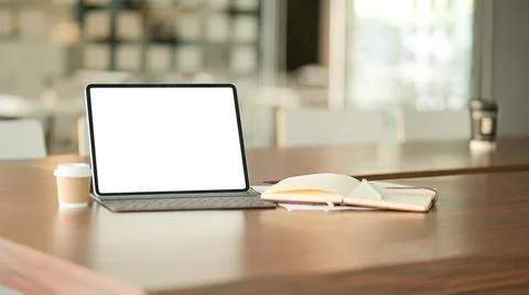 Blank screen laptop computer and a coffee in modern office with notebook. 库存照片