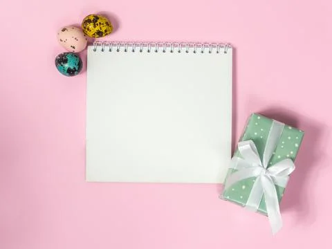 A blank sheet of paper surrounded by easter eggs on a pink background Stock Photos