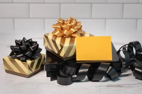 Blank sign no writing sitting on wrapped presents in gold and black paper bows Stock Photos