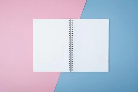 Blank spiral notebook on pastel background. Flat lay of home office desk. Stock Photos