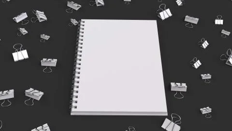 Blank spiral notebook with white binder clips on black table Stock Illustration