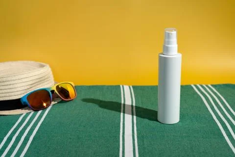 Blank sunscreen bottle sun hat and sunglasses on beach towel Stock Photos