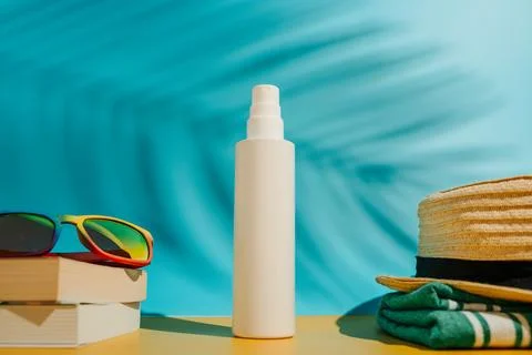 Blank sunscreen bottle sun hat and sunglasses books on beach Stock Photos