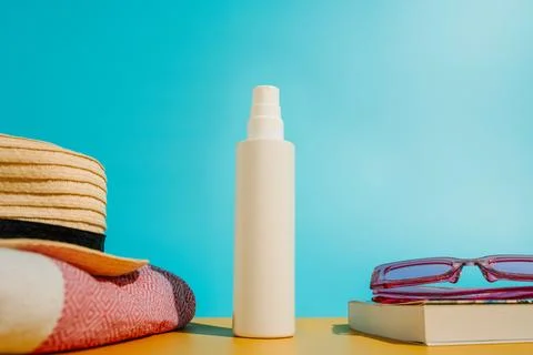 Blank sunscreen bottle sun hat and sunglasses books on beach Stock Photos