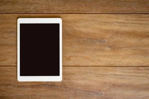 Blank Tablet computer on wood table background with space for text. Stock Photos
