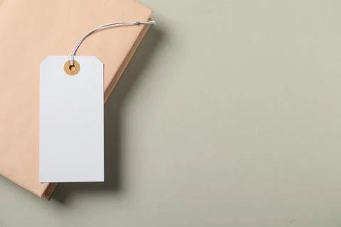 Blank tag with string and book on grey background, top view. Space for text Stock Photos
