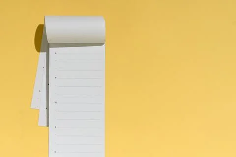 Blank tear-off planner notepad hangs open on yellow background with copy spac Stock Photos