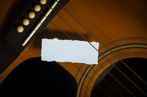 Blank torn paper on guitar strings. Copy space and music concept Stock Photos