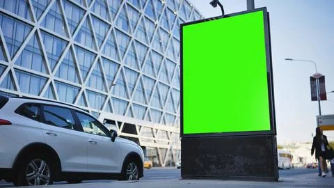 A blank vertical green screen billboard on a city street with a modern building Fotos de archivo