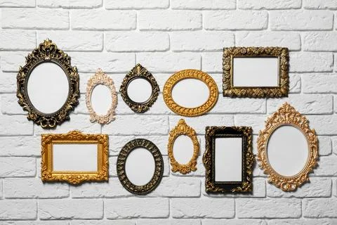 Blank vintage frames hanging on white brick wall. Mockup for design Stock Photos