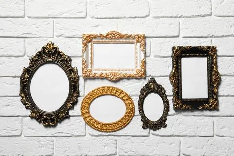 Blank vintage frames hanging on white brick wall. Mockup for design Stock Photos