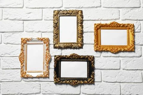 Blank vintage frames hanging on white brick wall. Mockup for design Stock Photos