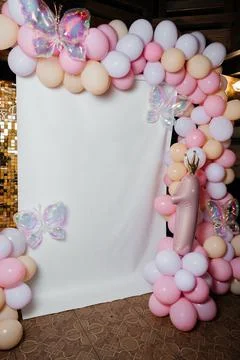 Blank white backdrop framed by pastel balloon arch with butterflies at girl.. Stock Photos