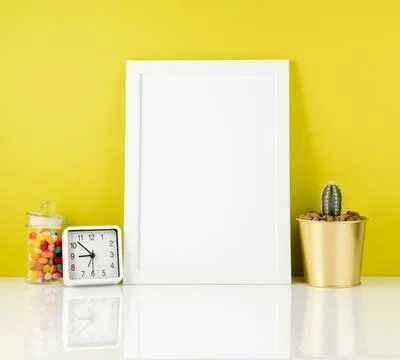 Blank white frame, clock, succulent, candy on white table agains Stock Photos