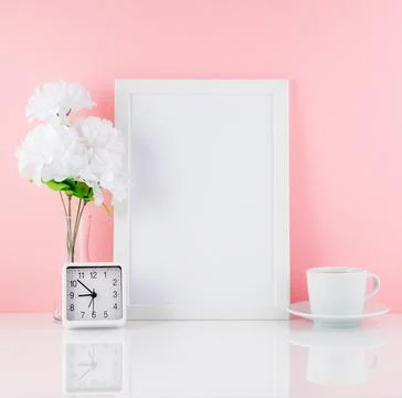 Blank white frame, flower, clock, cup of coffee or tea on a white table against Stock Photos
