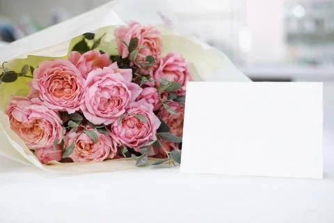 Blank white gift card on the background of a bouquet of flowers Stock Photos