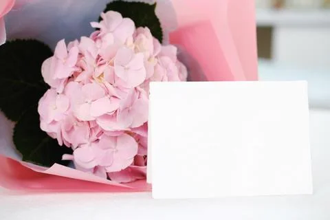 Blank white gift card on the background of a bouquet of flowers Stock Photos