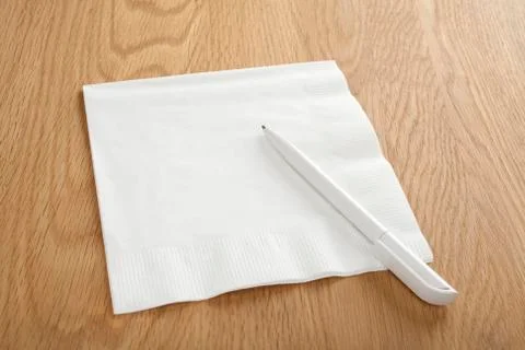 Blank white napkin or serviette and pen on wooden surface Stock Photos