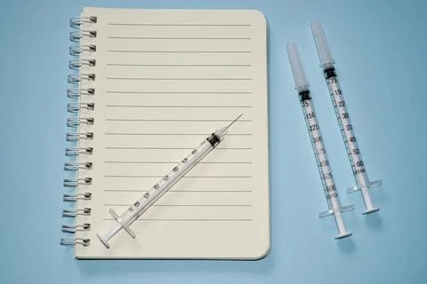 Blank white notepad with disposable injection syringes 库存照片