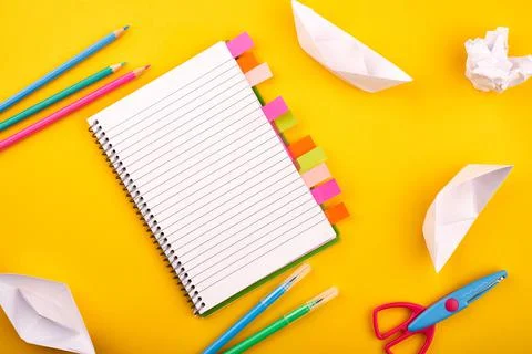 Blank white notepad with papers, pencils and scissors on yellow background Stock Photos