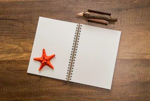 Blank white open notebook with orange starfish and color pencil on table Stock Photos