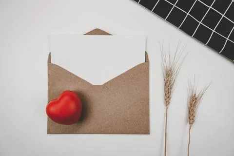 Blank white paper is placed on open brown paper envelope with red heart and B Stock Photos