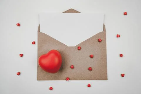 Blank white paper is placed on open brown paper envelope with red heart. Top Stock Photos