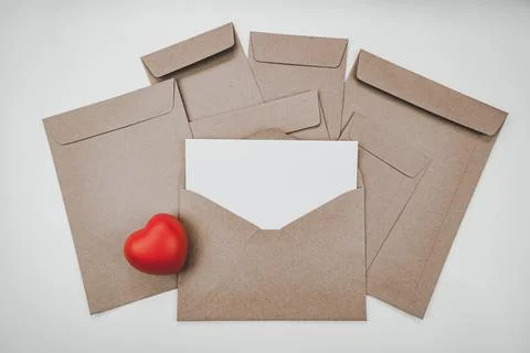 Blank white paper is placed on the open brown paper envelope with red heart. Foto stock