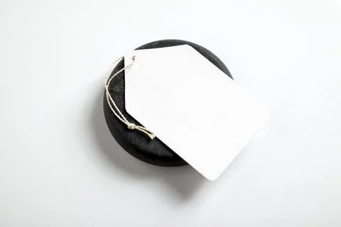 Blank white paper price tag with a string lying on a smooth black stone ove.. Stock Photos