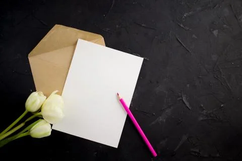 Blank white postcard flyer. Envelope kraft whith pensil and tulips. Flat lay. Foto stock