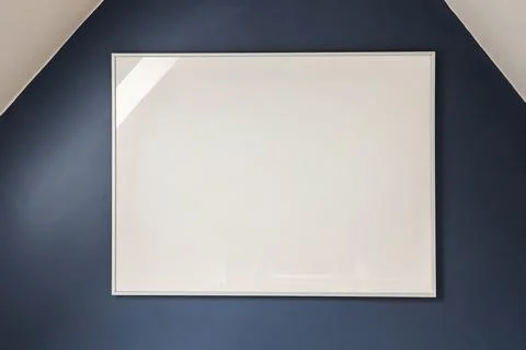 Blank white rectangular frame on dark navy wall with white ceiling, minimal.. Foto stock