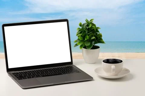 A blank white screen laptop, coffee cup, and vase are placed on a white des.. Stock Photos