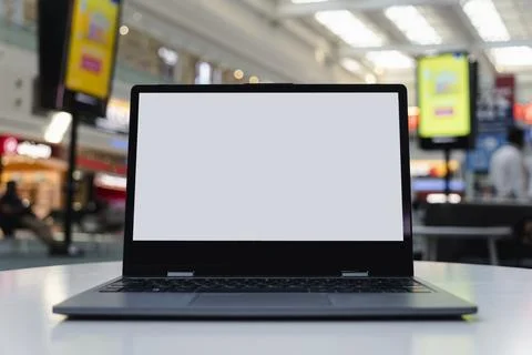 Blank white screen laptop computer on wood table with cafe restaurant abstrac Stock Photos