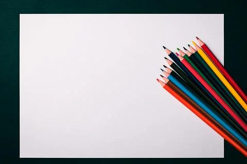 A blank white sheet and colored pencils for drawing on a plain textured backg Stock Photos