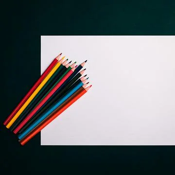 A blank white sheet and colored pencils for drawing on a plain textured backg Stock Photos