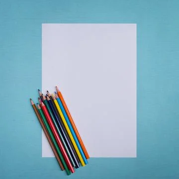 A blank white sheet and colored pencils for drawing on a plain textured backg Stock Photos