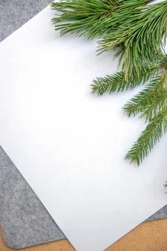 A blank white sheet is placed on a textured surface, adorned with fresh pine  Stock Photos