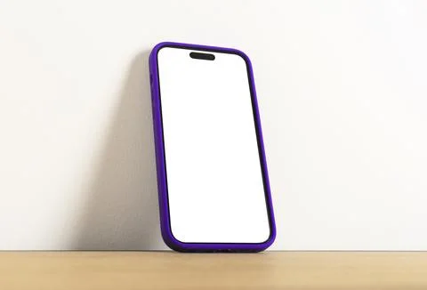Blank white smartphone screen mockup leaning against a wall on a wooden tab.. Stock Photos