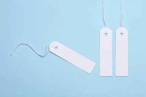 Blank white tags with string on blue background Stock Photos