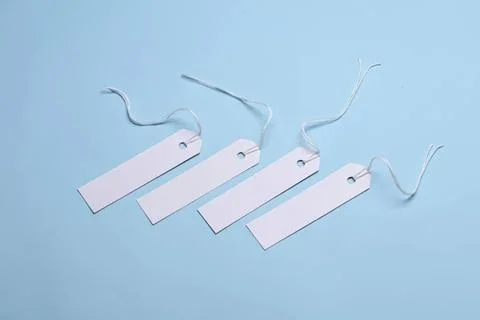 Blank white tags with strings on light blue background Stock Photos