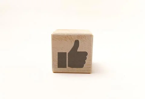 Blank wooden cube featuring a gray thumbs-up icon on natural grain texture,.. Stock Photos