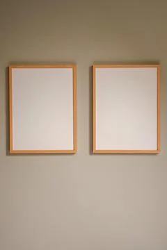 Blank woodenframes on a beige wall, creating a minimalist gallery mock up f.. Stock Photos
