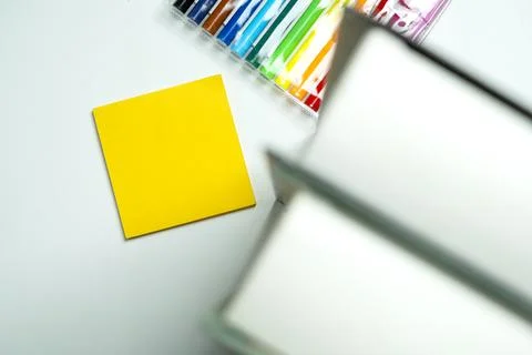 A blank yellow square sticky note placed on a light surface next to a row o.. Stock Photos