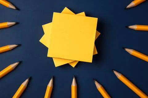 Blank yellow sticky note and pencil on navy blue table background Stock Photos