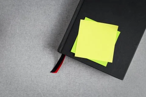 Blank yellow sticky note placed on black cover book with red and black bookma Stock Photos
